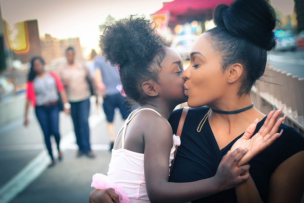 Mother holding and kissing daughter.